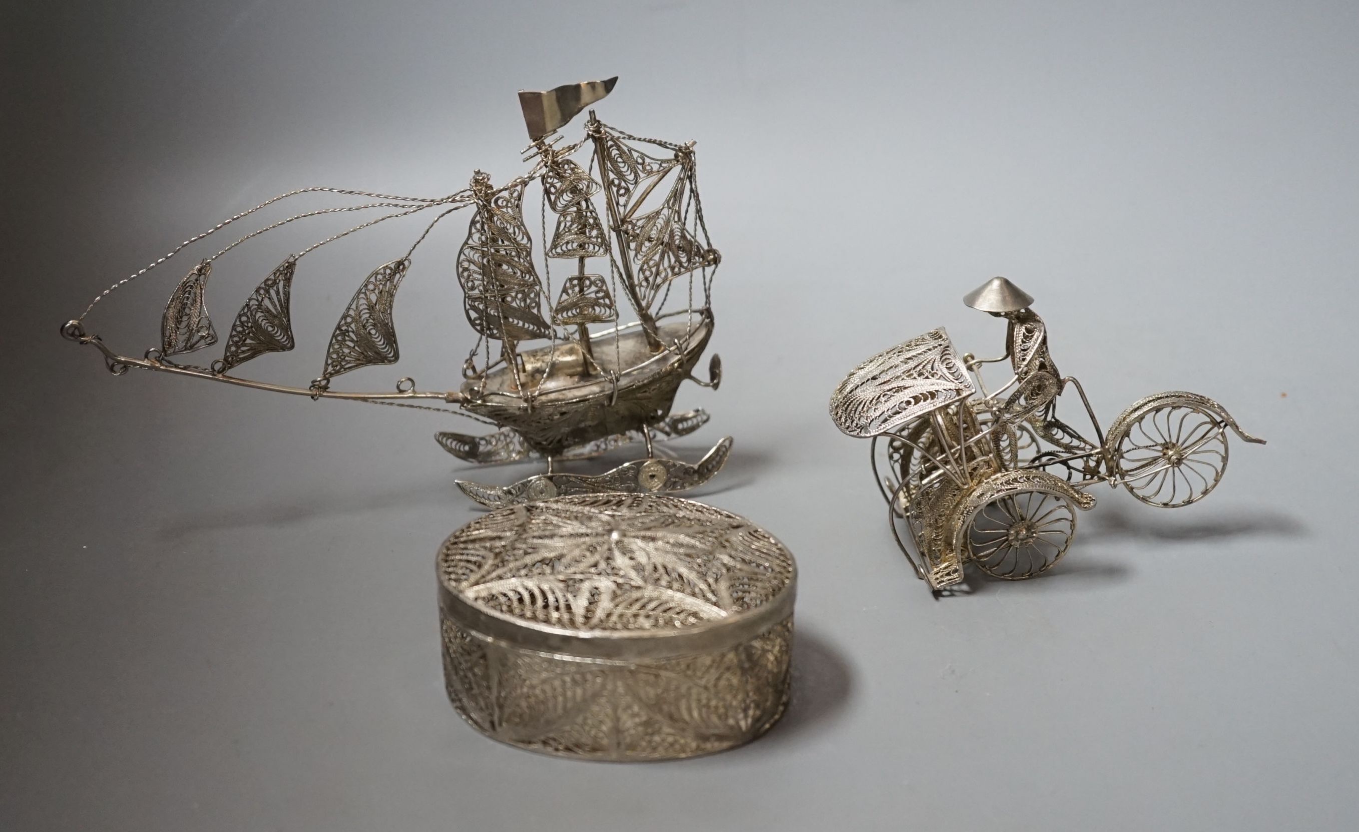 A Chinese filigree white metal model of a ship, length 19cm, a similar model of a rickshaw with driver and passenger and a similar oval box and cover